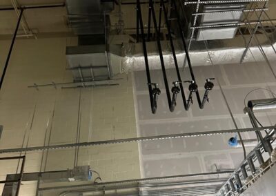 A complex network of ductwork, piping, and conduit systems suspended from a ceiling.