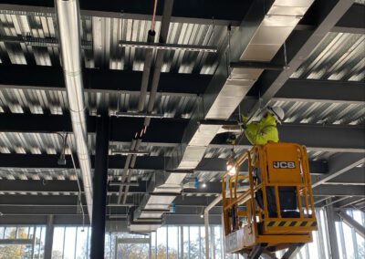 A construction worker on a yellow scissor lift working within an unfinished building interior.