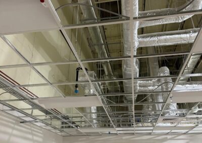 Ceiling view showing exposed ductwork, pipes, and electrical conduits in a commercial space.