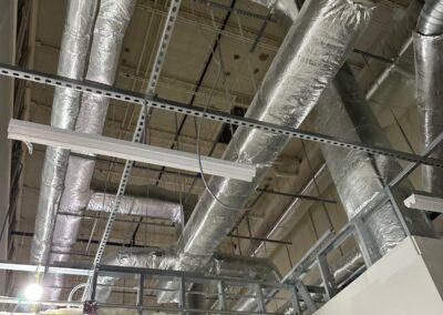 Insulated ductwork and metal pipes on the ceiling of an industrial space.